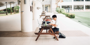 Etudiant travaillant sur son ordinateur sur une table de pique-nique en extérieur