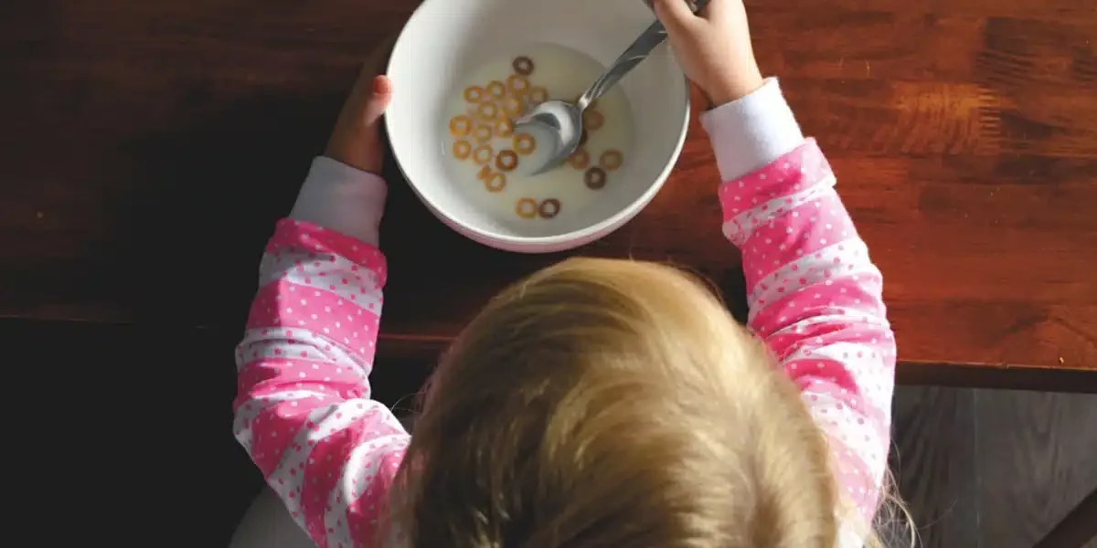 Petite fille au petit-déjeuner avec un bol de céréales